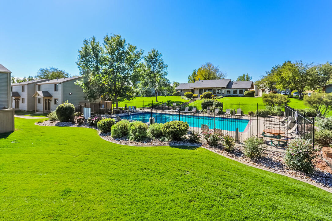 Fenced pool area with lush landscaping at The Hewing pet-friendly apartments in Fort Collins